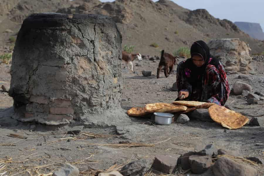 دختر روستایی بلوچ در حال پخت نان تنوری  